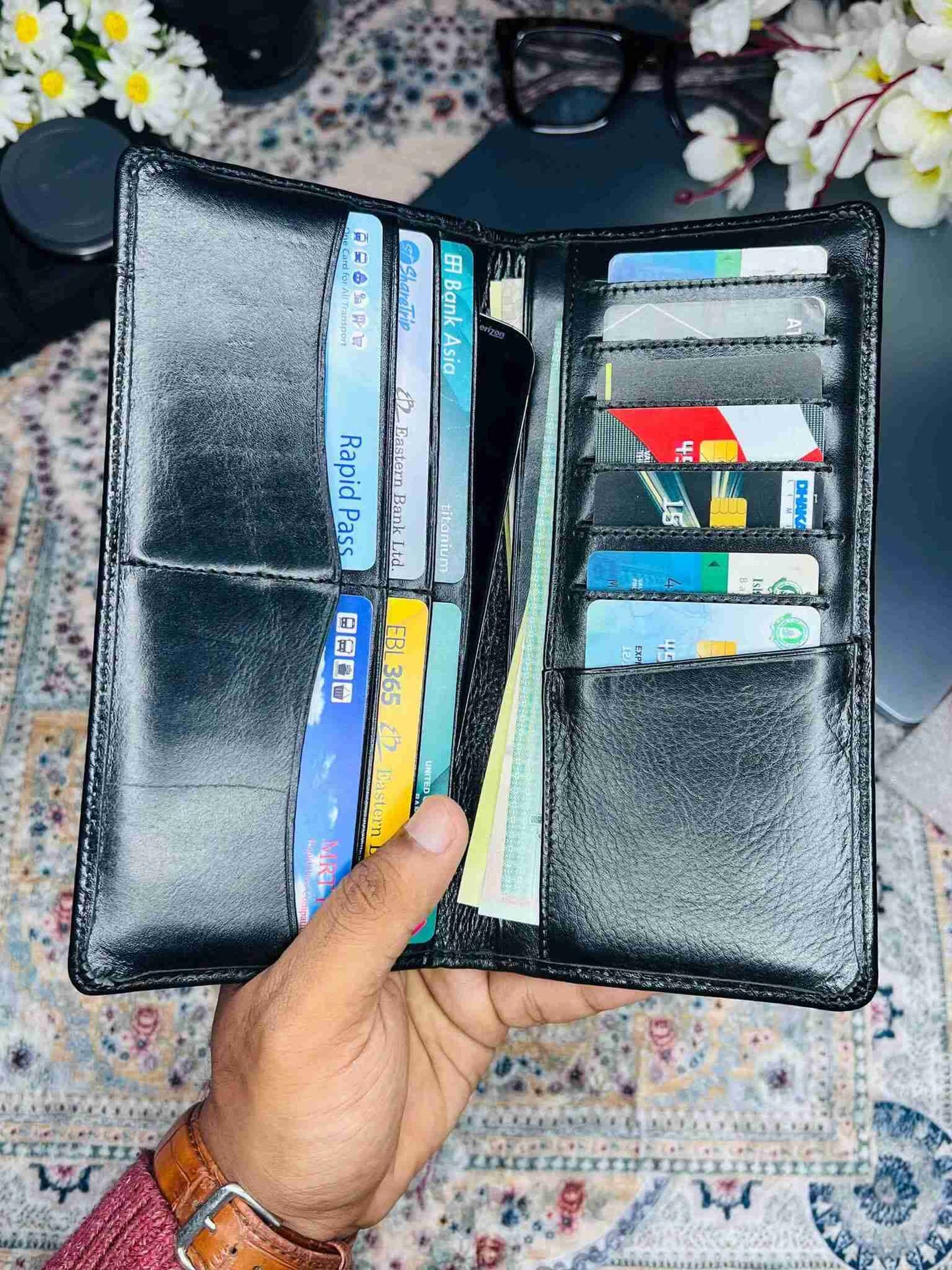 Luxury black genuine leather long wallet for men placed on a wooden desk